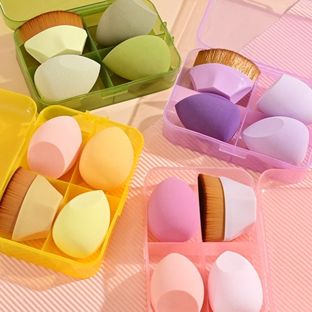Colorful makeup sponges in open containers on a pink background
